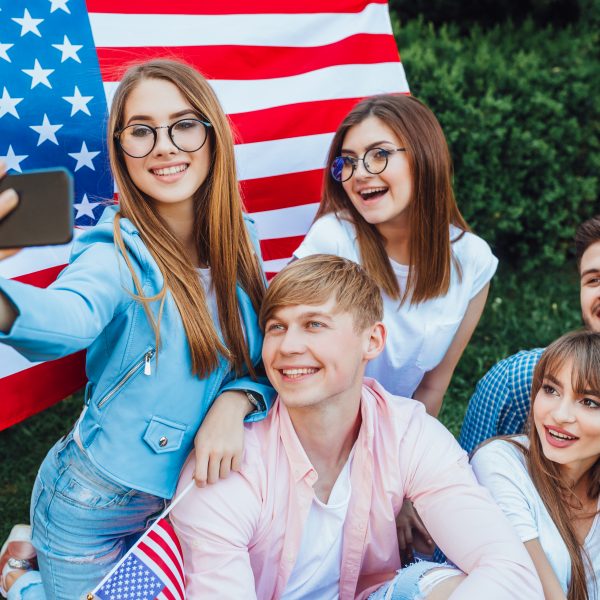 This is the US Independence Day! A group of young Americans doing sephi against the background of the American flag. Mobile phone close up.