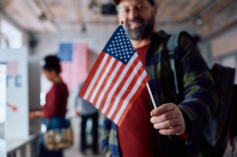 man-holding-flag-at-polling-place-on-election-day-2026-03-16-03-30-00-utc (1)